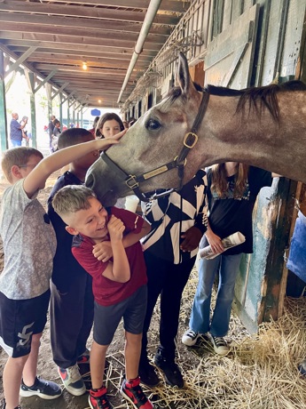 Students interacting with a horse during an Amplify Horse Racing program in Saratoga.